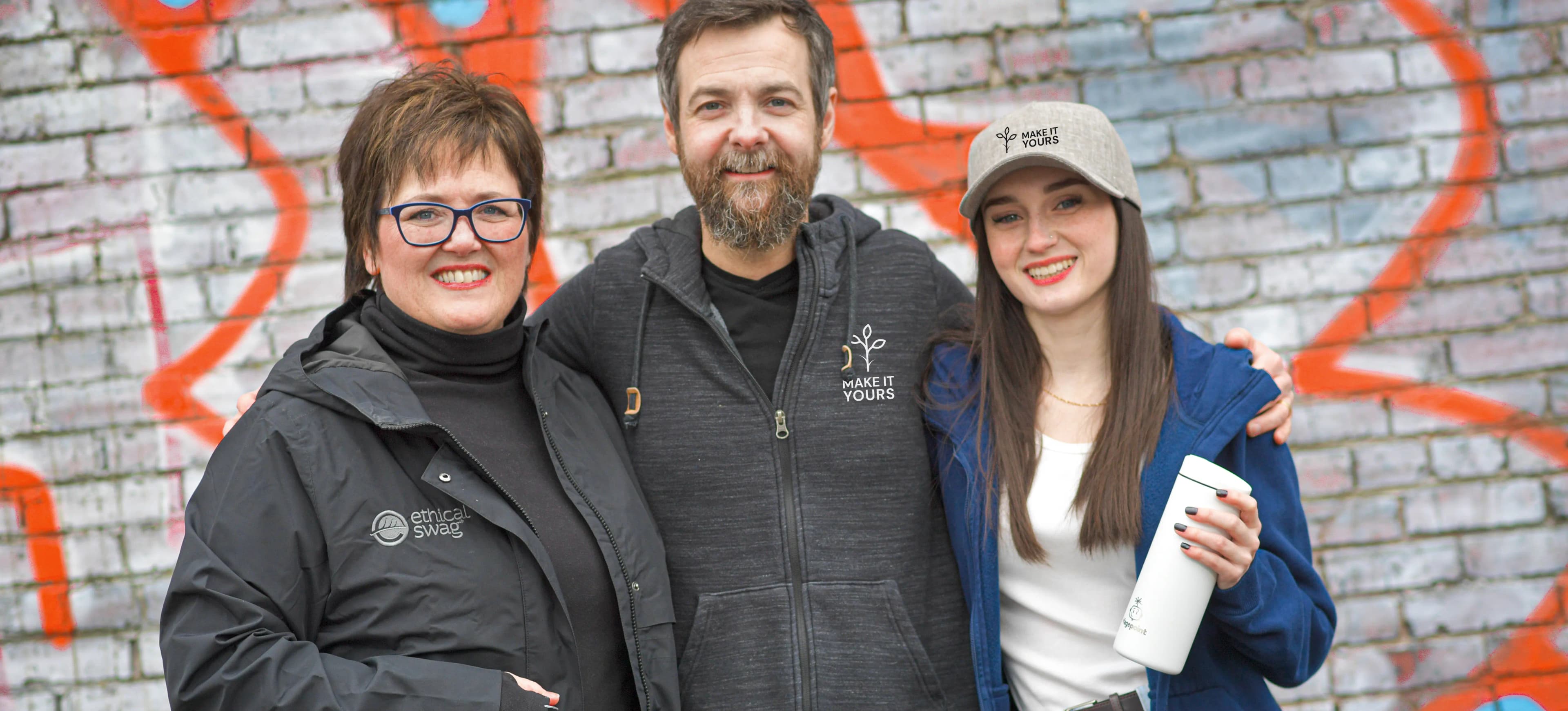 Three team members wearing branded apparel and holding custom swag